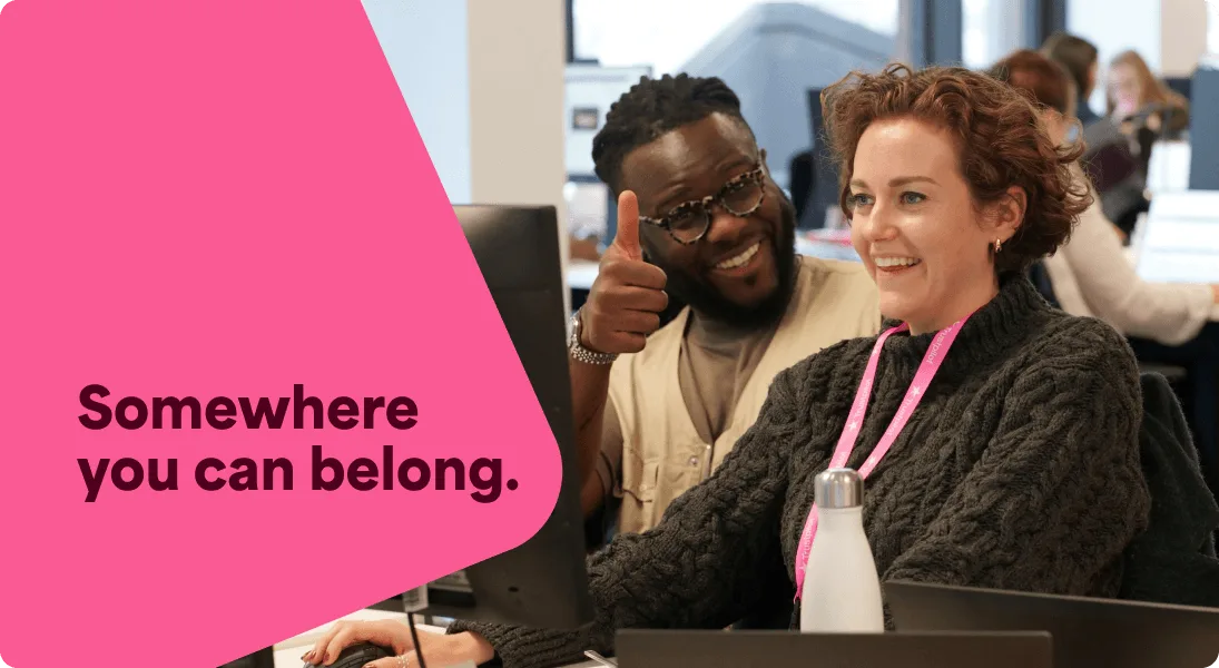 A photo of two Trustpilot employees smiling at their desk. The woman is looking at her laptop whilst the man is looking directly at the camera, giving a thumbs up gesture.