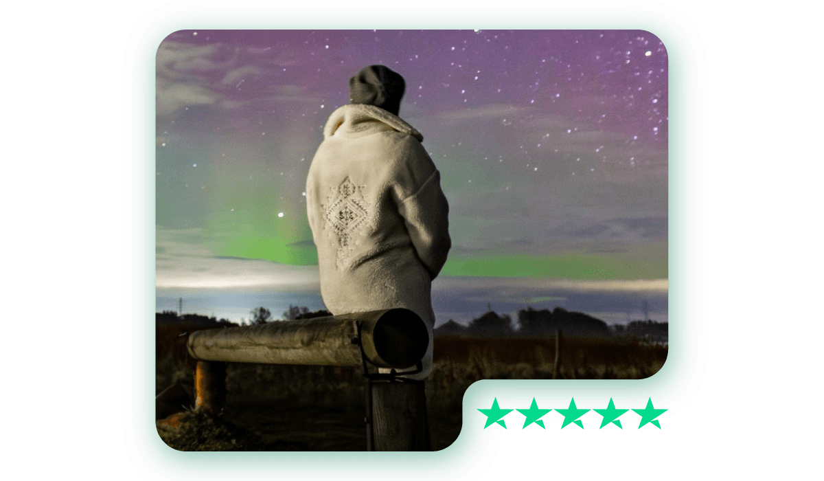 A photo of a person in a warm coat watching the Northern Lights under a starry sky, with a Trustpilot 5-star rating graphic in the corner.